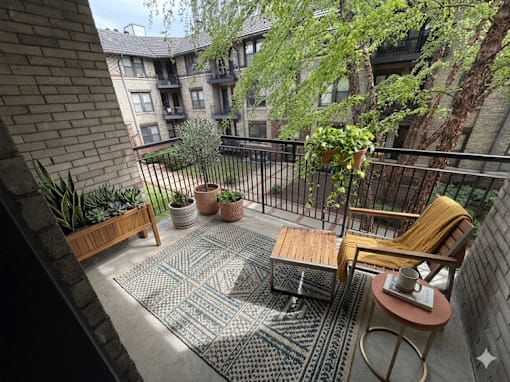 A balcony with a table, chairs, and potted plants.