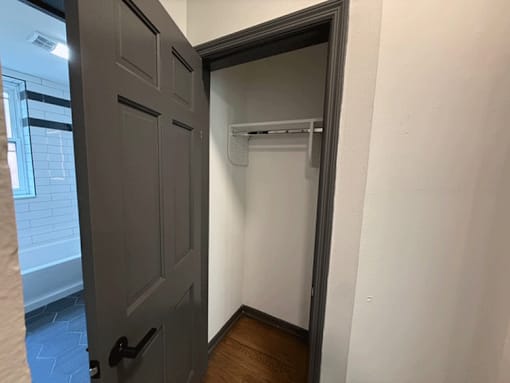 A white wall with a black door and a white shelf.