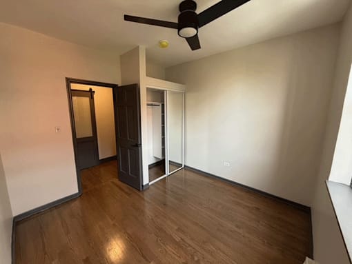 A room with a ceiling fan and wooden flooring.