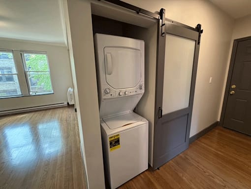 A white dryer is in a small closet.