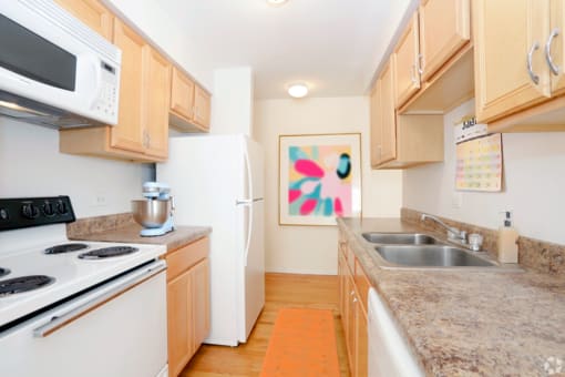 a kitchen with white appliances and granite counter tops and wooden cabinets