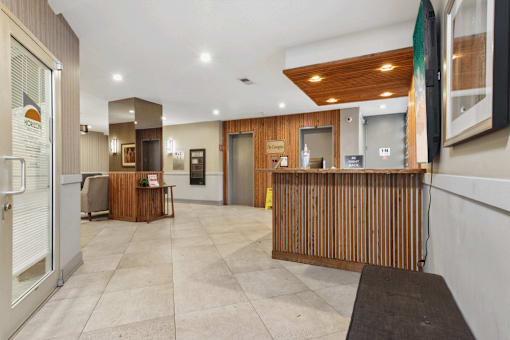 A reception area with a wooden counter and a black mat on the floor.