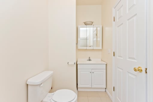 A white toilet sits next to a white sink in a small bathroom.