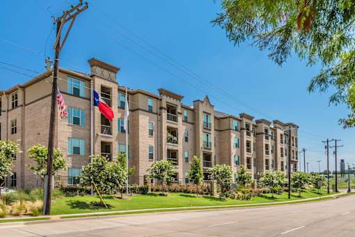 A row of apartment buildings with a clear blue sky above. at Atlas Point at Prestonwood Apartments , Carrollton