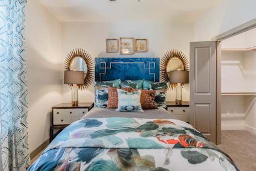 A bedroom with a large bed and a blue headboard at Atlas Point at Prestonwood Apartments , Carrollton, Texas