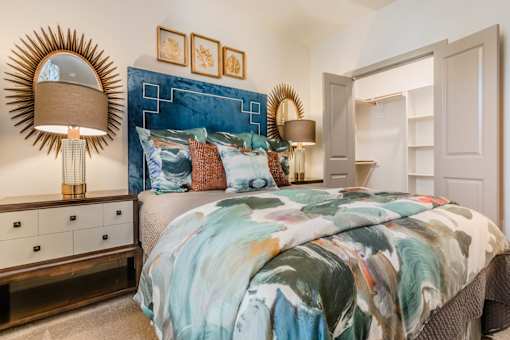 A bedroom with a bed, nightstands, and a mirror at Atlas Point at Prestonwood Apartments , Texas, 75010