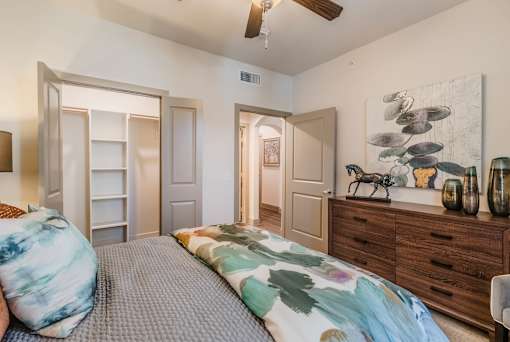 A bedroom with a bed, dresser, and ceiling fan at Atlas Point at Prestonwood Apartments , Carrollton, TX