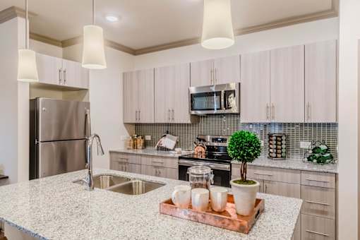 A kitchen with a granite countertop and a refrigerator. at Atlas Point at Prestonwood Apartments , Carrollton, TX, 75010