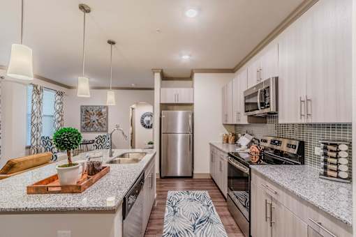 A kitchen with a refrigerator, oven, and sink at Atlas Point at Prestonwood Apartments , Texas