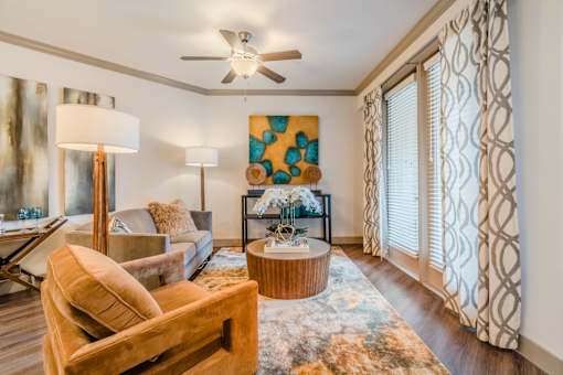 A living room with a brown chair and a painting on the wall. at Atlas Point at Prestonwood Apartments , Carrollton, Texas