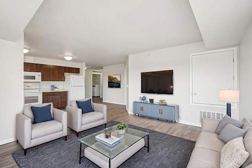 A living room with a glass coffee table and two chairs.