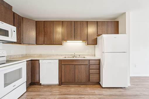 A kitchen with white appliances and wooden cabinets.