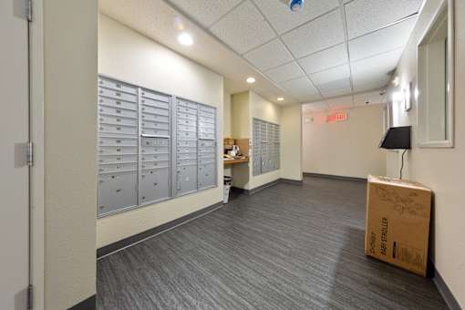A cardboard box with the word "STRUCTURE" on it is sitting on the floor of a room with a row of mailboxes on the wall.
