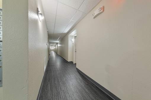 A long hallway with a wooden floor and white walls.