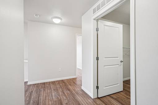 A white door is open to a room with wood flooring.