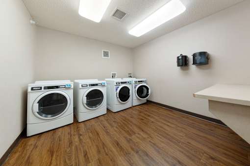 Three washing machines are lined up in a laundry room.
