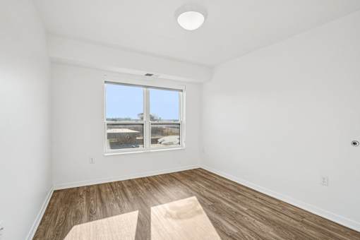 A room with a large window and wooden flooring.