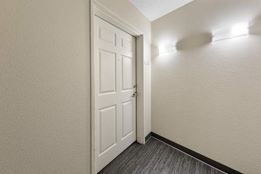 A white door is open to a hallway with lights on the wall.