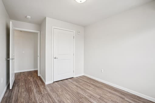 A room with a white door and a brown floor.