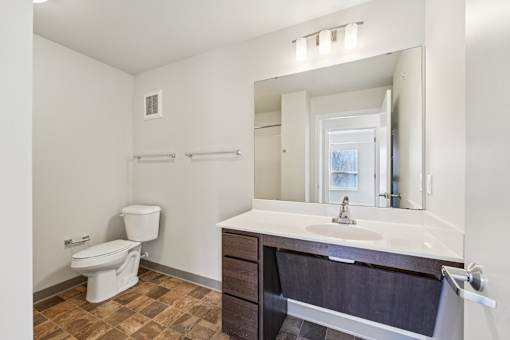 A bathroom with a toilet, sink, and mirror.
