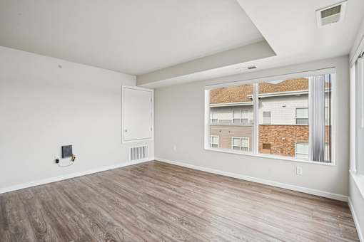 A room with a window showing a view of a building.