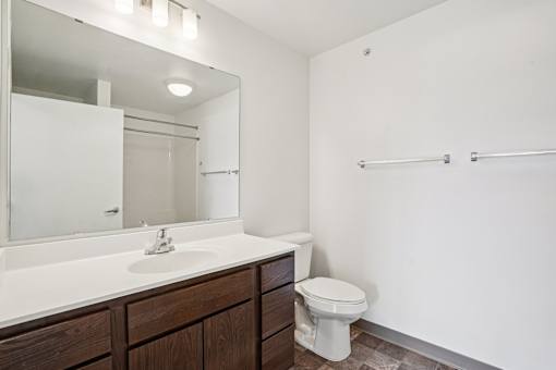 A bathroom with a toilet, sink, and mirror.