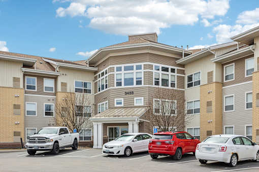 A row of cars are parked in front of apartment buildings.