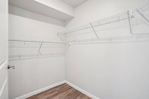 A white closet with a door and shelves.