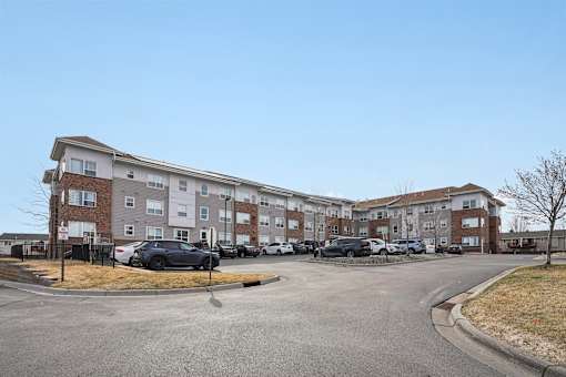 A parking lot in front of a large apartment complex.