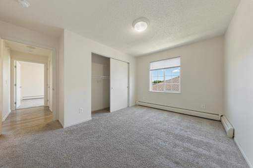 A spacious room with a carpeted floor and a window showing a building outside.