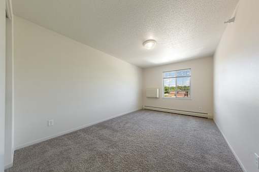 A room with a carpeted floor and a window.