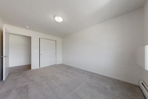 A spacious room with a carpeted floor and white walls.