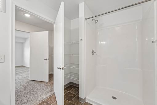 A white bathroom with a walk-in shower and a white door.