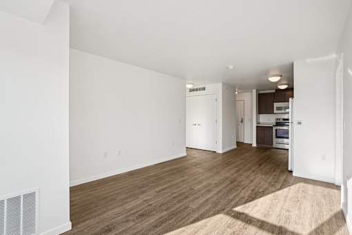 A spacious living room with a kitchen in the background.