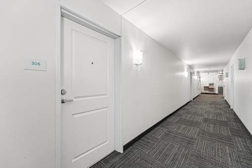 A hallway with a door on the left and a sign above it that says 306.