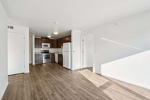 A kitchen with white appliances and wooden floors.