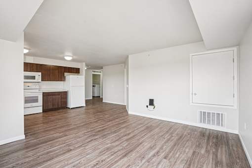 A kitchen with white appliances and wooden floors.