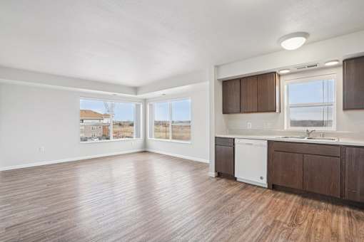 A spacious kitchen with wooden floors and white appliances.