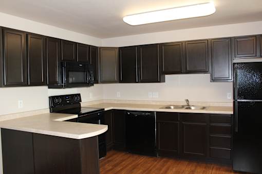 A kitchen with black cabinets and a white counter.