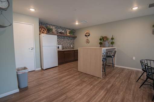 A kitchen with a wooden floor and a white refrigerator.
