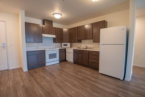 A kitchen with white appliances and brown cabinets.