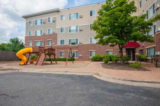a playground in front of an apartment building with a yellow slide