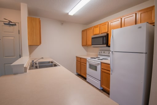 an empty kitchen with white appliances and wooden cabinets