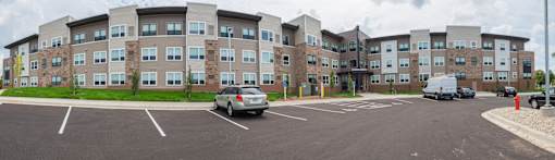 A parking lot in front of a large apartment building.