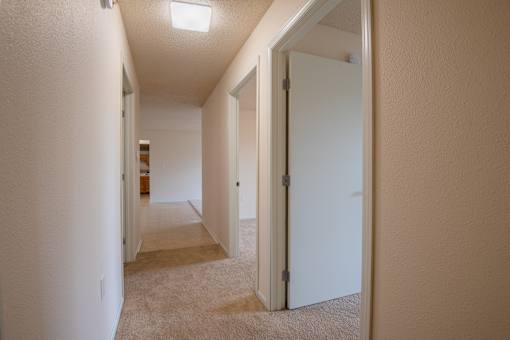 A hallway with a carpeted floor and white walls.