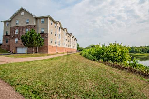 Apartment building with a tree in front and a grassy area in front of it.