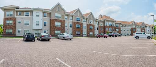 A parking lot in front of a large apartment building.