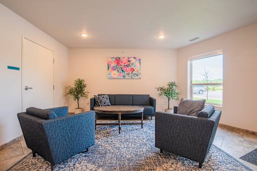 A living room with a blue rug and a painting on the wall.