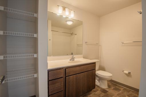 A bathroom with a toilet, sink, and mirror.