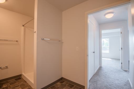 A white hallway with a door on the right and a window on the left.